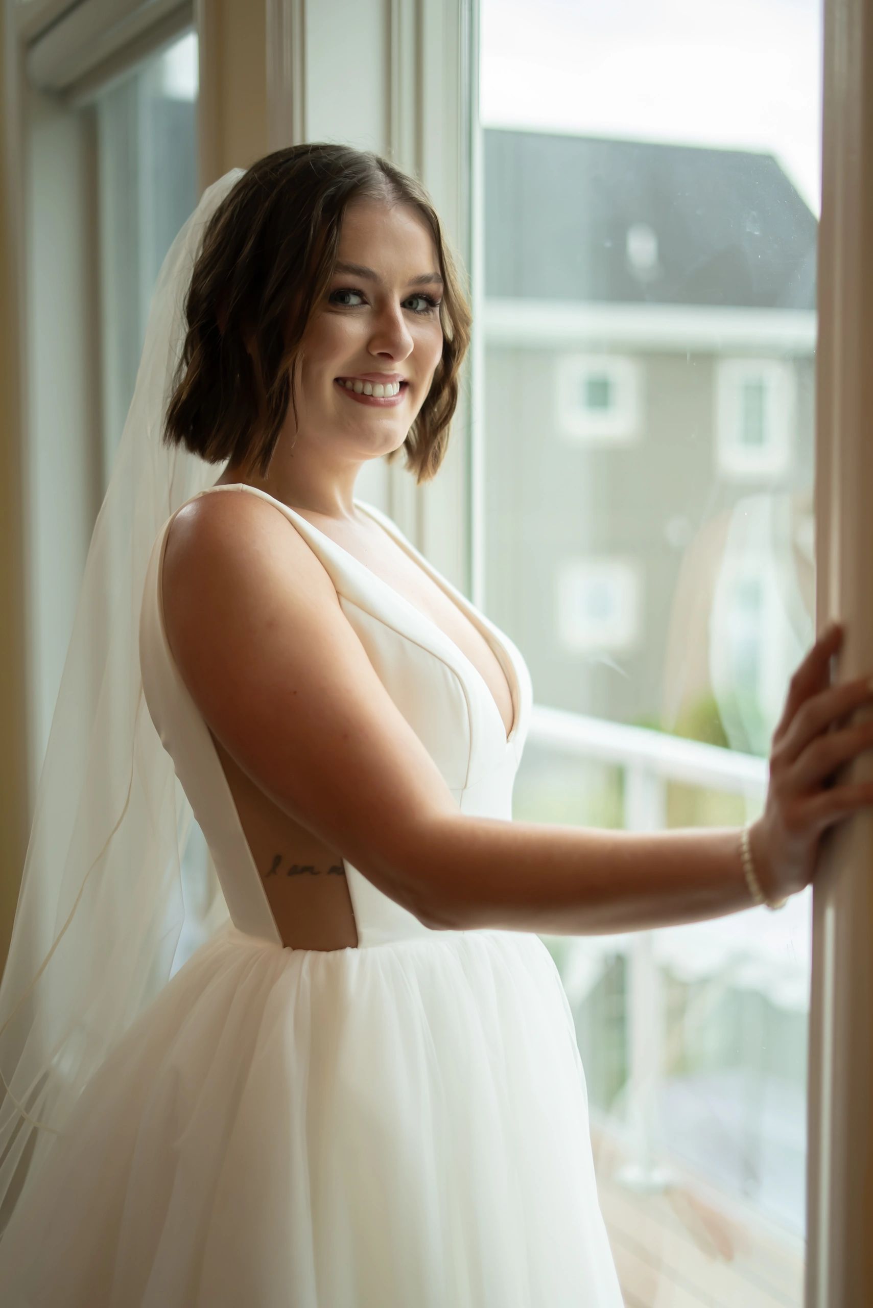 Bride in white dress by window